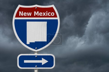 Téléchargez les photos : Road trip au Nouveau-Mexique, Panneau routier inter-états rouge, blanc et bleu avec mot Nouveau-Mexique et carte du Nouveau-Mexique avec fond de ciel orageux - en image libre de droit