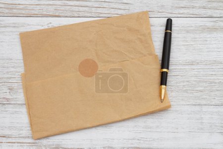 Photo for Brown crumpled butcher paper with a pen on weathered wood with a seal - Royalty Free Image