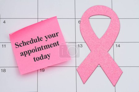 Planen Sie noch heute Ihren Termin für die Mammographie-Untersuchung mit rosa Schleife und Klebezettel auf einem Kalender