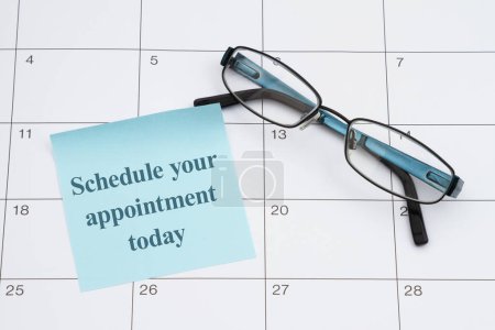 Photo for Schedule your appointment today for your eye doctors checkup with glasses and sticky note on a calendar - Royalty Free Image
