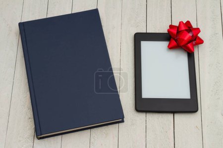 Photo for Retro old blue book and an ereader with gift bow on weathered desk for reading or school - Royalty Free Image