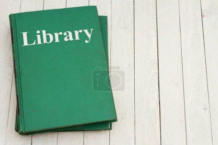 Photo for Getting books from library with retro old green book on weathered desk for reading or school - Royalty Free Image
