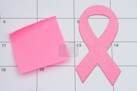 Zeit für die Mammographie-Untersuchung mit rosa Schleife und Klebezettel auf einem Kalender