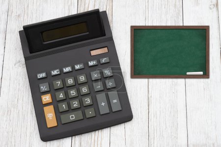 Téléchargez les photos : Le coût des frais de scolarité pour l'éducation avec une calculatrice noire avec un tableau sur un bureau en bois altéré - en image libre de droit