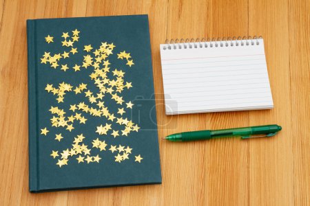 Photo for Retro old blue book with stars a notepad and pen on weathered desk for reading or school - Royalty Free Image