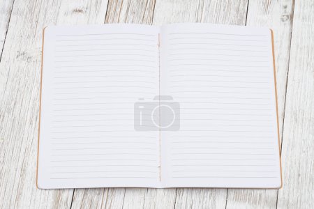 Foto de Cuaderno de notas de la página de papel de la revista de línea reglamentada en el escritorio envejecido para escribir o escribir en diario - Imagen libre de derechos