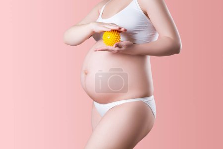 Photo for Pregnant woman with massage ball in white underwear on pink background, pregnancy concept - Royalty Free Image