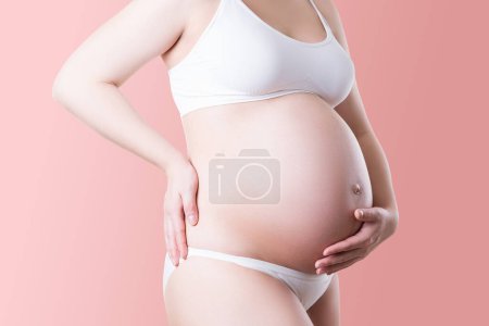 Photo for Pregnant woman in white underwear on pink background, pregnancy concept - Royalty Free Image