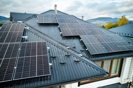 Foto de Sistema de paneles solares fotovoltaicos en el techo de la casa. Módulos solares modernos instalados en la casa. Concepto de alternativa, energía renovable y autonomía del hogar. - Imagen libre de derechos
