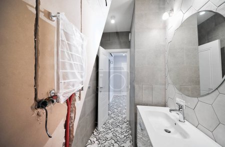 Foto de Apartamento baño con secador de toallas eléctrico antes y después de la restauración. Piso antiguo y baño recién reformado con lavabo y espejo. - Imagen libre de derechos