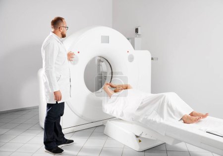 Foto de Tomografía computarizada médica o escáner de resonancia magnética. Radiólogo masculino presiona botón de resonancia magnética para examinar paciente femenino. - Imagen libre de derechos