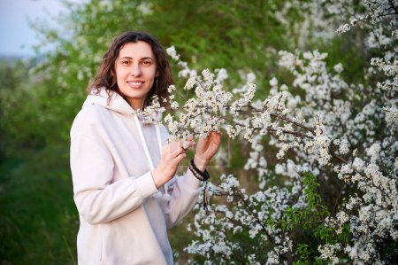 Woman allergic enjoying after treatment from seasonal allergy at spring. Portrait of happy young woman smiling in front of blossom tree at springtime. Spring allergy concept.