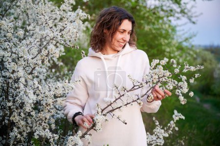 Woman allergic enjoying after treatment from seasonal allergy at spring. Happy young woman smiling in front of blossom tree at springtime. Spring allergy concept.