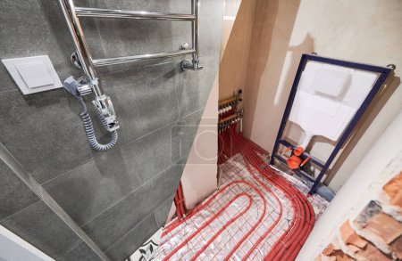 Comparison of washroom lavatory before and after renovation. Old apartment restroom with underfloor heating pipes and new renovated toilet room with electric towel dryer.