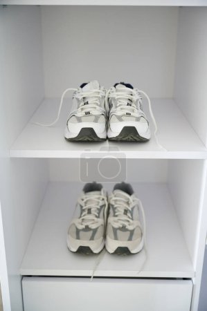 Two pairs of sneakers on white shelves. New pairs of matching shoes for active lifestyle.