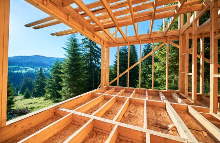 Photo for Wooden frame house under construction near forest. Beginning of new construction of cozy house on the edge of forest in mountains. Concept of modern ecological construction and modern architecture. - Royalty Free Image