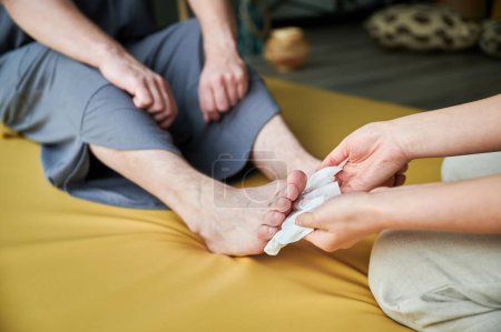 Téléchargez les photos : Gros plan de femme masseuse nettoyage par tissus humides doux clients masculins pieds avant le massage thaï sur le tapis. Vue recadrée. - en image libre de droit