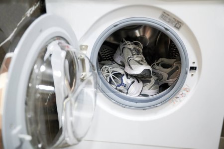 Téléchargez les photos : Deux paires de baskets en machine à laver. Chaussures sales doivent être lavées après l'exercice à l'extérieur. - en image libre de droit