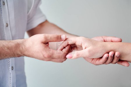 Close up of two hands engaging in delicate touch. Mans and womans hands on white neutral background. Husband holding hand of his lovely wife. Concept of affection, support, and mutual respect.