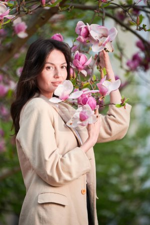 Woman allergic enjoying after treatment from seasonal allergy at spring. Portrait of happy young woman smiling in front of blooming magnolia tree at springtime. Spring allergy concept.