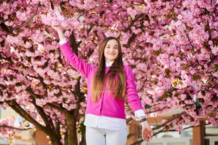 Woman allergic enjoying after treatment from seasonal allergy at spring. Portrait of happy beautiful woman smiling in front of blooming sakura tree at springtime. Spring allergy concept.