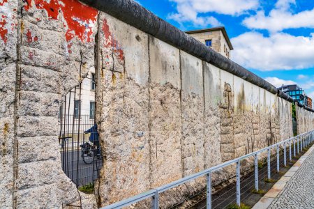 Photo for Red Paint Hole Bicycle Remains of Berlin Wall Public Park Berlin Wall. Wall Separated West Berlin from East Berlin of the East Germany from 1961 to 1989 to prevent East Germans in Communist East Berlin and East Germany to flee to Democratic West Berl - Royalty Free Image