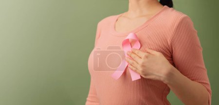 Photo for Breast Cancer Awareness Campaign Concept. Women Healthcare. Close up of a Young Female Touching Pink Ribbon on her Thorax - Royalty Free Image