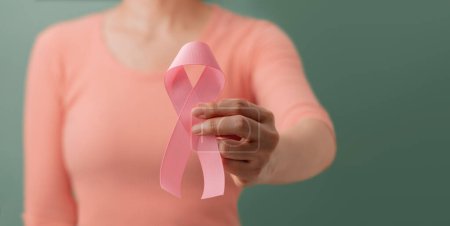 Photo for Breast Cancer Awareness Campaign Concept. Women Healthcare. Close up of a Young Female Brings a Pink Ribbon into the Front. - Royalty Free Image