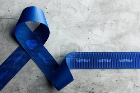 Photo for Prostate Cancer Awareness Campaign Concept. Men Healthcare. Close up of a Blue Moustache Ribbon  Lying on Rough Grey Cement Concrete background, Top View - Royalty Free Image