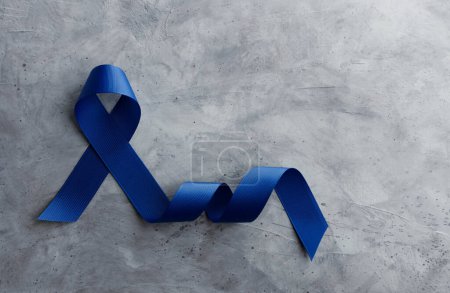 Photo for Prostate Cancer Awareness Campaign Concept. Men Healthcare. Close up of a Blue Ribbon  Lying on Rough Grey Cement Concrete background, Top View - Royalty Free Image