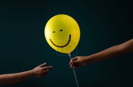 Photo for Happiness Day, Encoragement Concept. Happy and Optimistic Mind, Well Mental Health. Person giving a Smiling Balloon to another - Royalty Free Image