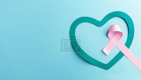Photo for Breast Cancer Awareness Campaign Concept. Women Healthcare. Close up of a Pink Ribbon Lying inside a Teal Heart, Top View - Royalty Free Image