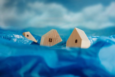 Photo for Climate Change Effect, Environment Issue. Conceptual Photo. Wooden Miniature House in Flood made from Plastic Waste. Environmental Impact. Global Issues, Desertification, Water, Pollution, and Energy - Royalty Free Image