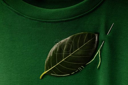 Photo for ESG and Sustainability Lifestyle. Environmental Care Concept. Close up of a Green Leaf Embroidered with a Sewing Needle on t-shirt. Eco-Friendly, Organic Cloth - Royalty Free Image