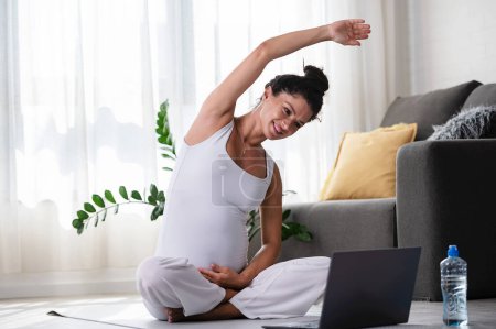 Foto de Hermosa mujer embarazada haciendo yoga en línea clase - Imagen libre de derechos