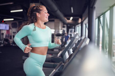 Photo for Young woman on treadmill in gym - Royalty Free Image