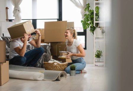 Foto de Feliz pareja joven desempacar o empacar cajas y mudarse a un nuevo hogar - Imagen libre de derechos