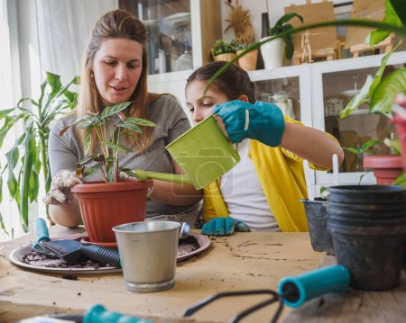 Photo for Mother and daughter repotting plants together at home garden. Spring gardening. - Royalty Free Image