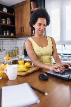 Téléchargez les photos : Femme afro-américaine utilisant un ordinateur portable à la maison - en image libre de droit