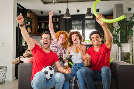 Téléchargez les photos : Groupe multiethnique de jeunes s'amusant, regardant un match de football à la télévision - en image libre de droit