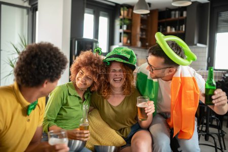 Foto de Grupo multiétnico de jóvenes divirtiéndose, viendo un partido de fútbol en la televisión. Animando a Irlanda. - Imagen libre de derechos