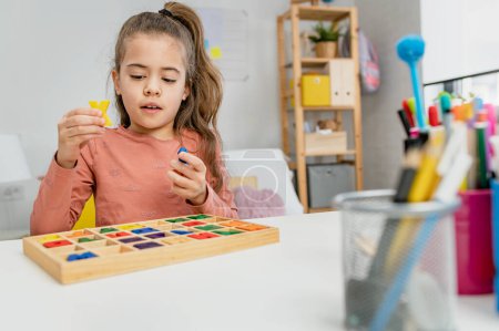 Téléchargez les photos : Petite écolière jouant avec des lettres en bois. Apprendre à écrire. - en image libre de droit