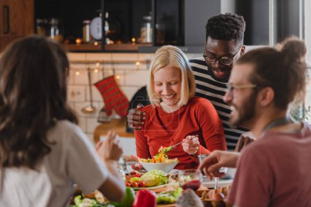 Photo for Young diverse people having a holiday party at home, preparing food, drinking, talking and enjoying - Royalty Free Image