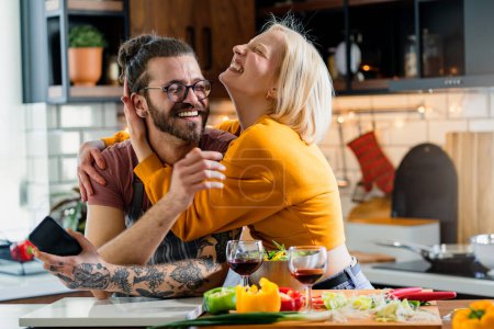 Photo for Young cheerful couple preparing a healthy vegan lunch at home - Royalty Free Image