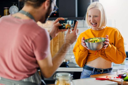 Photo for Young cheerful love couple preparing a healthy vegan lunch at home and have fun - Royalty Free Image