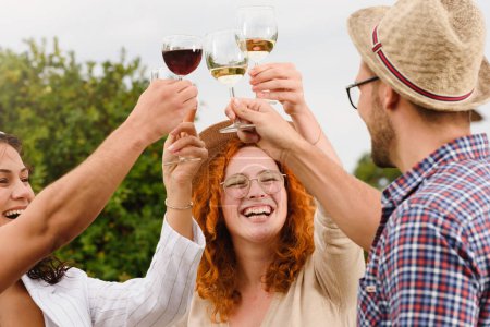 Foto de Amigos felices bebiendo vino en el viñedo - Imagen libre de derechos