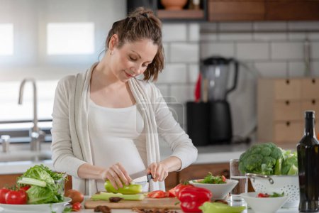 Téléchargez les photos : Jeune femme enceinte préparant des aliments sains avec des fruits et légumes - en image libre de droit