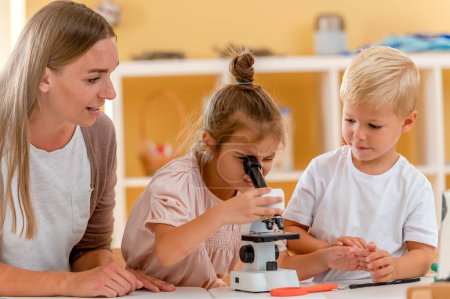 Téléchargez les photos : Les jeunes enfants regardent à travers le microscope tout en faisant un projet préscolaire scientifique. STEM dans le concept de l'éducation. - en image libre de droit