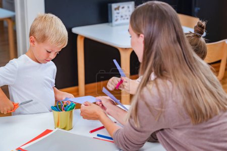 Photo for The teacher helps a child to make some paper crafts. Developing Fine motor skills for toddlers and preschoolers - Royalty Free Image
