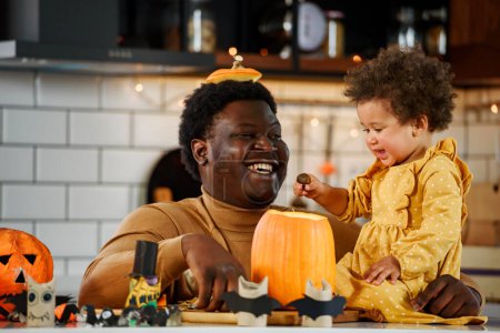 Photo for Happy halloween. african-american girl and her father holding a pumpkin - Royalty Free Image